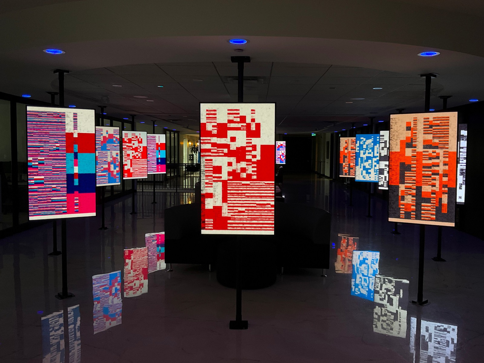 Montreal installed on freestanding screens at Suburbs Gallery, with red, blue and orange compositions reflected in the floor