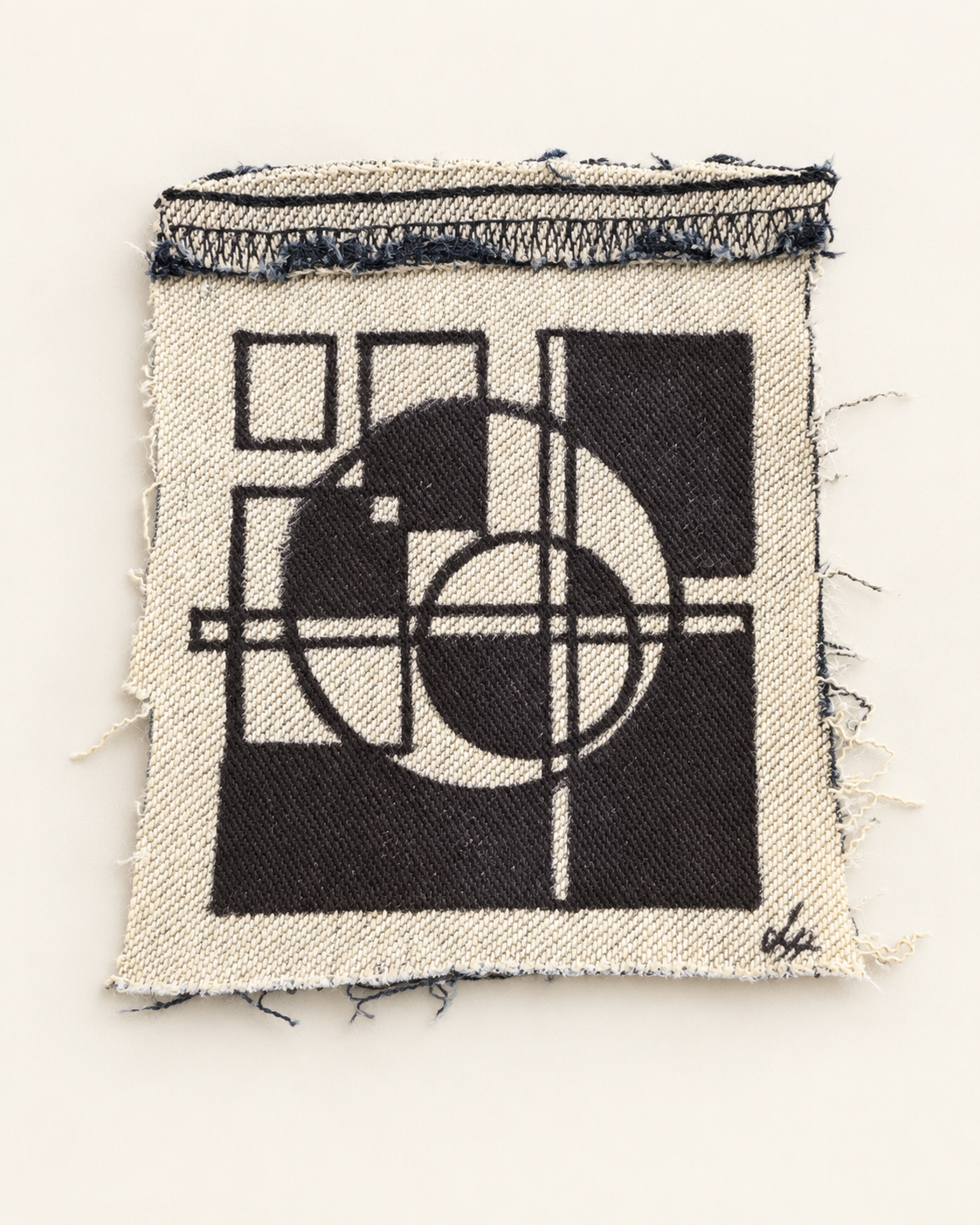 Interlocking black circles, blocks and outlined squares on cream denim with a stitched upper edge.